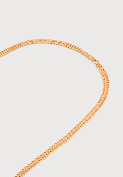 Collier chaîne en or fin avec des maillons ovales étroitement liés, disposé en boucle lâche sur un fond blanc uni.