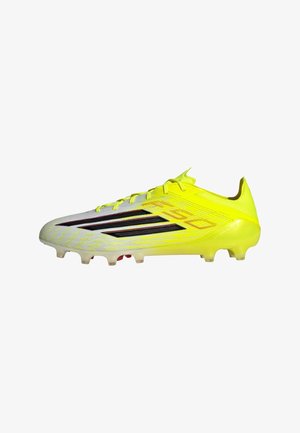 Crampon de football jaune avec une tige synthétique texturée, des détails en rayures noires, une semelle moulée et plusieurs crampons coniques pour la traction.