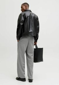 Must mustast nahkjakker, hallid ruudulised püksid, must käekott ja mustad kingad. Sile tekstuur, klassikaline disain, sobiv vorm.