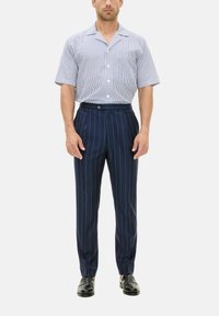 Camicia a maniche corte, con bottoni, a strisce bianche e blu abbinata a pantaloni a righe blu navy. Tessuto liscio con una vestibilità su misura.