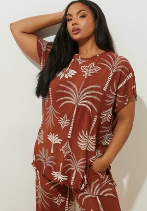 Brown patterned shirt and pants set featuring palm tree and leaf designs in white. Loose fit with scalloped edges, short sleeves, and pockets.