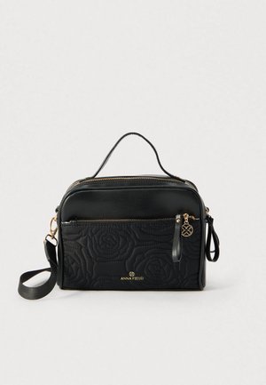 Čierna kabelka s prešívaným vzorom ruží, zlatými kovovými doplnkami a dvoma priehradkami na zips. Má hornú rúčku a nastaviteľný popruh.