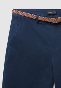 Pantaloni blu navy con una texture liscia, dotati di tasche laterali e una cintura intrecciata marrone con una fibbia dorata, etichettati "CALLIOPE."