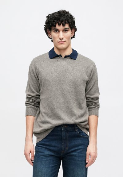 Hall hallitud kampsun ja sinise kraega, millel on pikad varrukad ja lõõgastunud istuvus. Kandatud tume siniste teksadega. Lihtne disain ja pehme tekstuur.