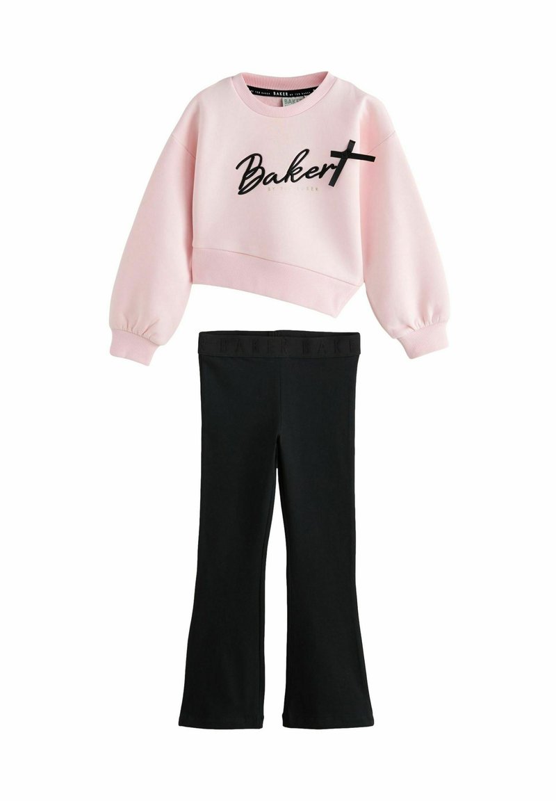Felpa cropped rosa con la scritta "Baker" in nero corsivo e una croce, abbinata a leggings neri a campana. Tessuto morbido con vita elasticizzata.