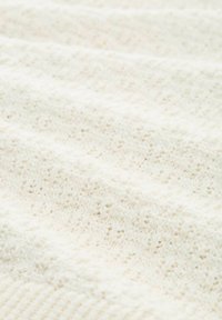 Tessuto bianco con texture che presenta un motivo lavorato a maglia con sezioni in rilievo, creando un aspetto morbido e stratificato.