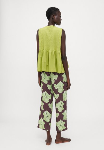 Lime green sleeveless top with textured detailing, paired with wide brown trousers featuring large green floral prints.
