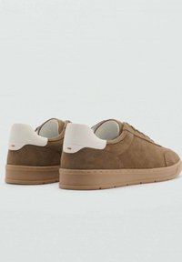 Brown suede sneakers with a low profile, featuring a white heel tab, textured paneling, and a tan rubber sole.
