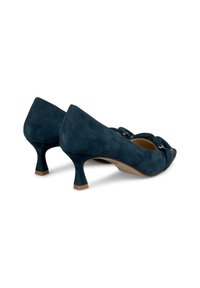 Talons en daim bleu marine avec un design à bout pointu, présentant un petit talon courbé et des sangles décoratives avec des accents métalliques.