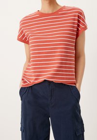 Camiseta de rayas en color coral y blanco, textura acanalada, mangas cortas, cuello redondo, corte relajado, combinada con pantalones cargo en color azul marino.