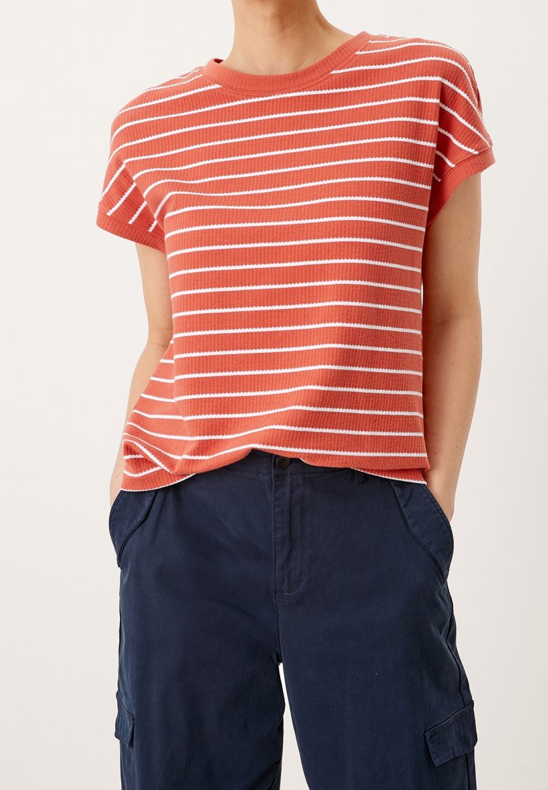 Camiseta de rayas en color coral y blanco, textura acanalada, mangas cortas, cuello redondo, corte relajado, combinada con pantalones cargo en color azul marino.