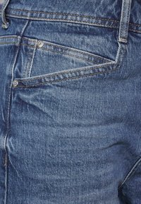 Sininen farkkuhousut, joissa on klassinen viiden taskun muotoilu, selkeä ompelu ja hieman kulunut pinta vaalealla pesulla.