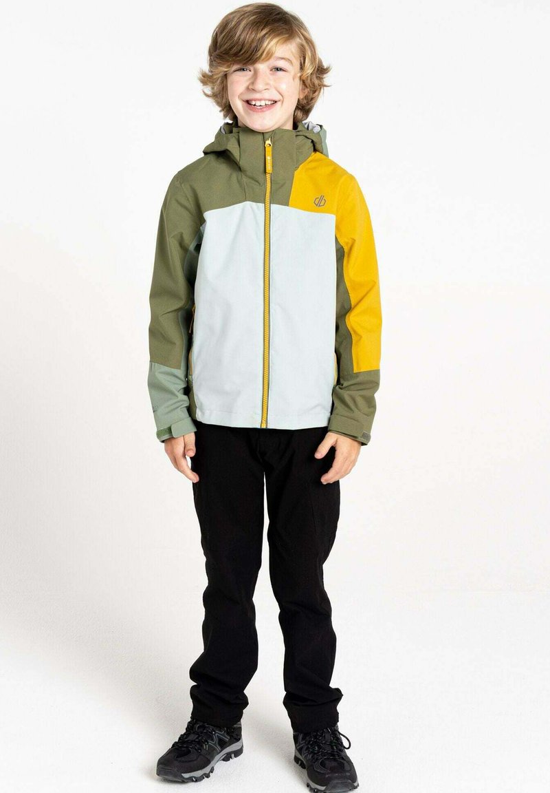 Wasserabweisende Jacke in Grün, Grau und Gelb mit durchgehendem Reißverschluss, verstellbare Kapuze und elastischen Bündchen; kombiniert mit schwarzen Hosen und Schuhen.