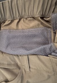 Pantalon marron avec une taille élastique et une doublure en mesh gris ventilé visible à l'intérieur de la taille.