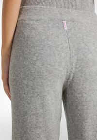 Grijze, fuzzy gebreide leggings met een brede, geribde tailleband. Voorzien van een klein roze logo-label dicht bij de bovenkant. Gladde textuur en aansluitende pasvorm.