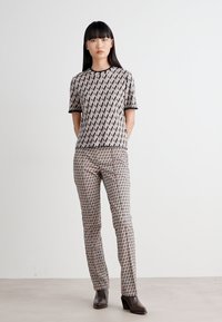 Hemd mit kurzen Ärmeln und enganliegenden Hosen aus gemustertem Stoff in gedeckten Tönen von Rosa und Beige, mit einem runden Halsausschnitt und kontrastierendem Besatz.