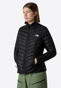 Czarna puchowa kurtka z zapięciem na zamek, stójką i poziomymi przeszyciami. Posiada boczne kieszenie oraz logo The North Face na klatce piersiowej.