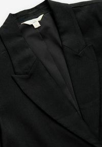 Black blazer with a structured lapel design, made of textured fabric. Interior lining is a contrasting solid color, featuring sharp cuts at the shoulders.