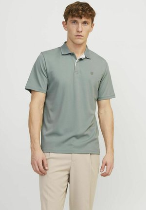Camiseta polo en verde claro, confeccionada en una tela suave con cuello y mangas cortas. Presenta un logotipo sutil en el pecho y un detalle de contraste en el cuello.