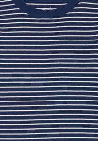 Marineblaue Baumwoll-T-Shirt mit horizontalen weißen Streifen, runder Ausschnitt und Textetikett nahe dem Kragen. Weiches, leichtes Material.