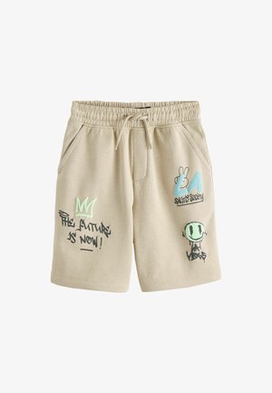 Bézs elasztikus derékú rövidnadrág elülső zsebekkel, graffiti-stílusú szöveggel és szimbólumokkal, többek között "A jövő most van!" és egy mosolygós arc "LA Vibes" felirattal.