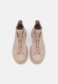 Hochschnitt-Sneaker aus weichem beigem Stoff mit samtartiger Textur, ausgestattet mit einer runden Gummisohle und zentralem Schnürverschluss.