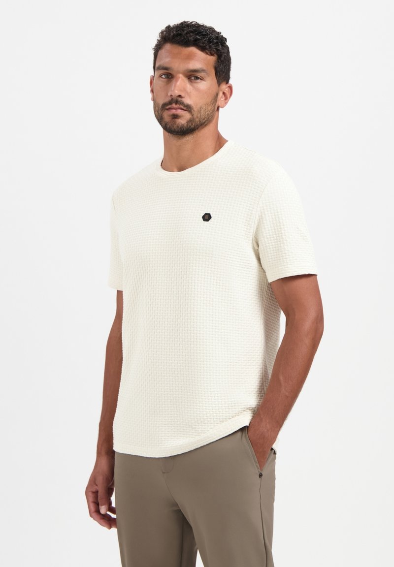 Korte mouwen crèmekleurig textiel shirt met een ronde hals, met een klein zwart hexagonaal logo op de borst. Gekocht met beige broek.