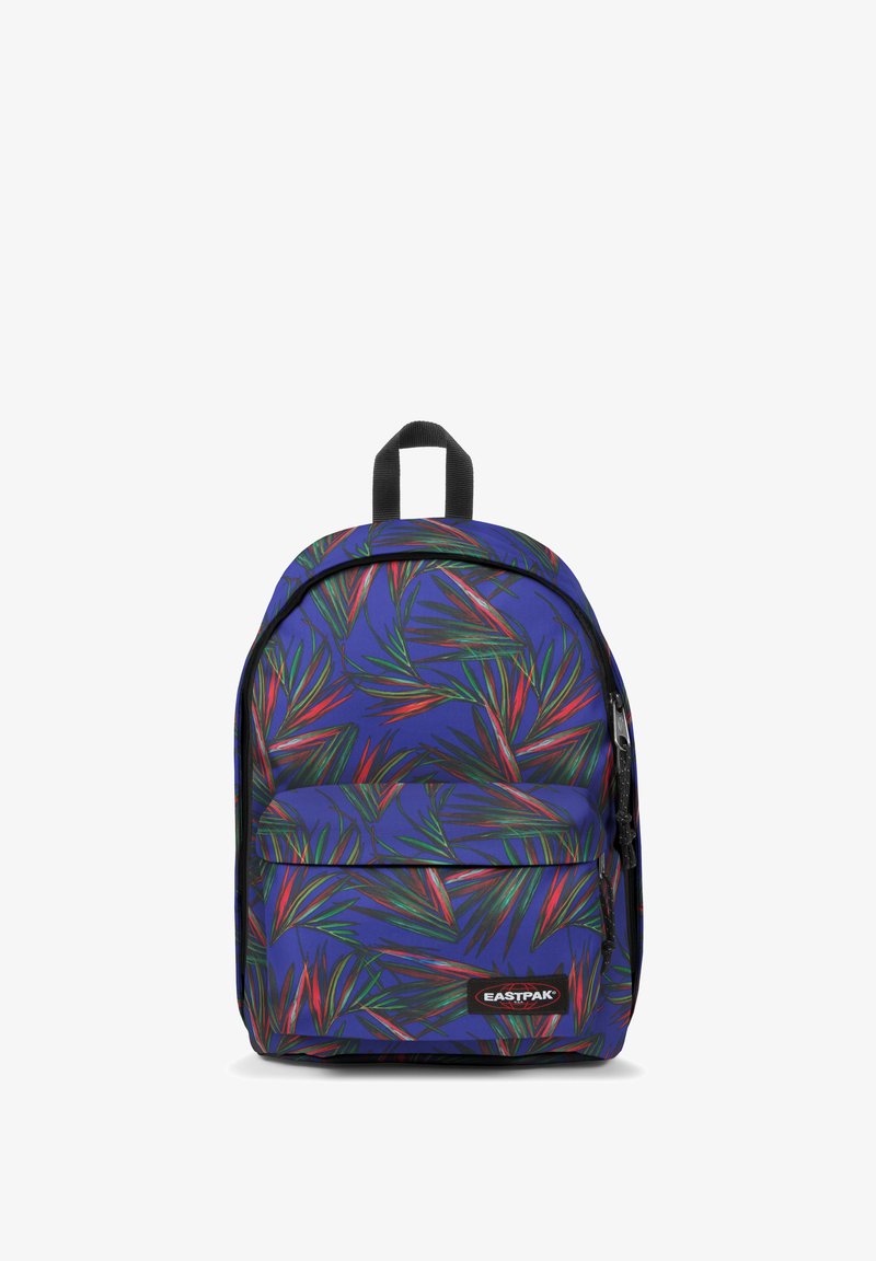 Mochila con un fondo morado que presenta patrones de hojas verdes y rojas. Tiene un asa superior y un bolsillo frontal con cremallera. Etiqueta de la marca visible.