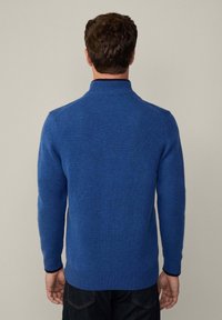 Suéter azul de punto con un cuello alto, puños y dobladillo acanalados. Textura suave con un patrón sólido, diseño ajustado.
