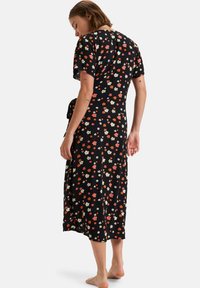 Robe maxi florale noire, avec des manches courtes, un corsage ajusté et une jupe fluide ornée de petites fleurs multicolores.