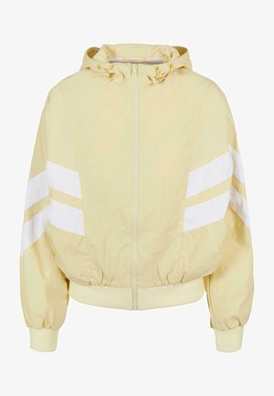 Chaqueta con capucha de color amarillo claro con rayas blancas, cierre de cremallera, puños y dobladillo elásticos, y tejido texturizado. Diseño deportivo clásico.