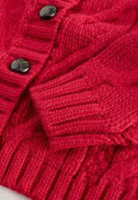 Rode gebreide cardigan met gestructureerde patronen, voorzien van grote zwarte knopen en geribbelde mouwen. Zachte, dikke garen voor warmte.