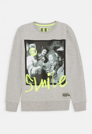 Grauer Sweatshirt mit einem schwarz-weißen Grafikbild von Menschen und einem leuchtend gelben Smiley-Gesicht sowie dem Text "SMILE" in Neon-Gelb auf der Vorderseite.