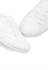 White athletic shoes made of mesh and synthetic materials, featuring a lace-up design and a textured sole for grip.