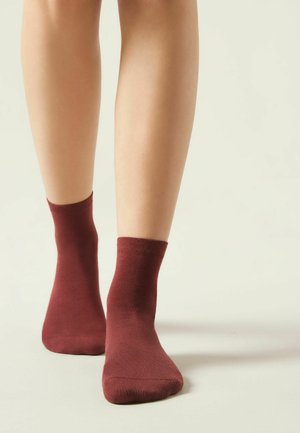 Burgundy bomullsstrumpor till anklarna med ribbat manschett, figurpassande design och slät textur, presenterade mot en neutral bakgrund.