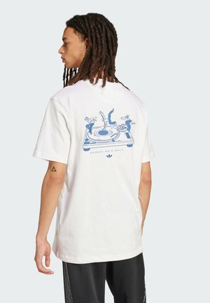 Hvid bomulds-t-shirt med et blåt grafisk design på ryggen, der viser mennesker, der danser på et pladespiller. Korte ærmer, afslappet pasform.