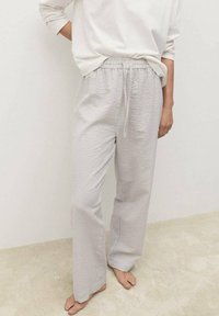 Pantaloni da pigiama grigi chiari realizzati in un morbido tessuto texturizzato; dotati di una fascia elastica in vita, un laccetto e una vestibilità rilassata. Un motivo sottile aggiunge dettagli.
