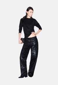 Zwarte glinsterende gebreide trui gecombineerd met hoge zwarte broek met een glanzend zebrapatroon en een enkellange snit.