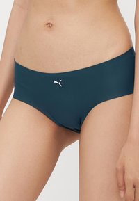 Fundo de bikini azul-escuro com um tecido suave e elástico. Apresenta um logótipo branco da Puma na frente. O design inclui um corte de altura média.