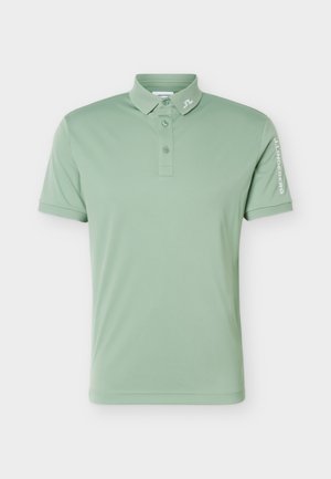 Polo vert clair à manches courtes avec trois boutons, petit logo sur le col et nom de la marque sur la manche droite.