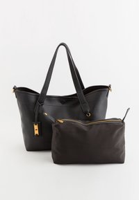 Stor sort tekstureret tote bag med to håndtag, prydet med guldhardware. Inkluderer en aftagelig sort pose med lynlås.