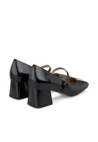 Talons en cuir verni noir avec un bout pointu, un talon carré et une sangle de cheville réglable avec un détail de boucle ronde.