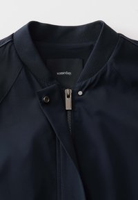 Marine bomberjack met een gladde stof, ribbelkraag, metalen rits en drukknoopsluiting, met binnenin een label waarop "someday" staat.