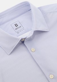 Camicia azzurra chiara con un motivo testurizzato, dotata di colletto classico e bottoni beige. Etichetta del marchio visibile all'interno del colletto.