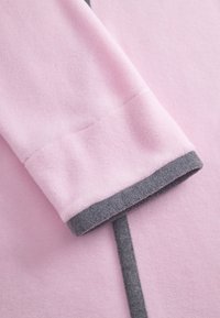 Close-up of a pink fleece sleeve with a gray cuff and matching gray trim on the garment.