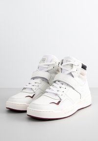 Witte hoge sneakers met een soepele leren bovenkant, veters en klittenbandsluiting, paarse accenten en een chunky rubberen zool.