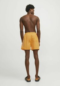 Bañadores naranja para hombre con cinturilla elástica, un bolsillo trasero y detalle del logo blanco en el costado. Tela suave y ligera.