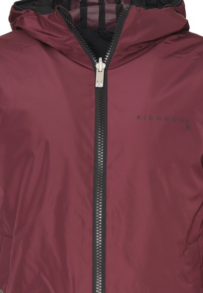 Giacca bordeaux con zip frontale, colletto alto e cappuccio. Caratterizzata da una texture liscia e lucida e logo "RICHMOND" stampato in nero.