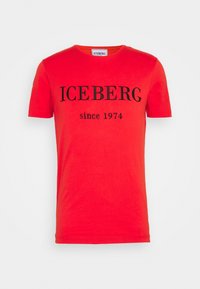 Camiseta de algodón roja de manga corta, con la leyenda "ICEBERG since 1974" impresa en negro en la parte frontal. Cuello redondo y textura suave.