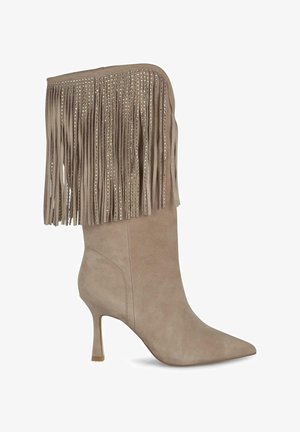 Bottine en suède beige avec un bout pointu, un talon stiletto et des franges décoratives rehaussées de petits clous métalliques.